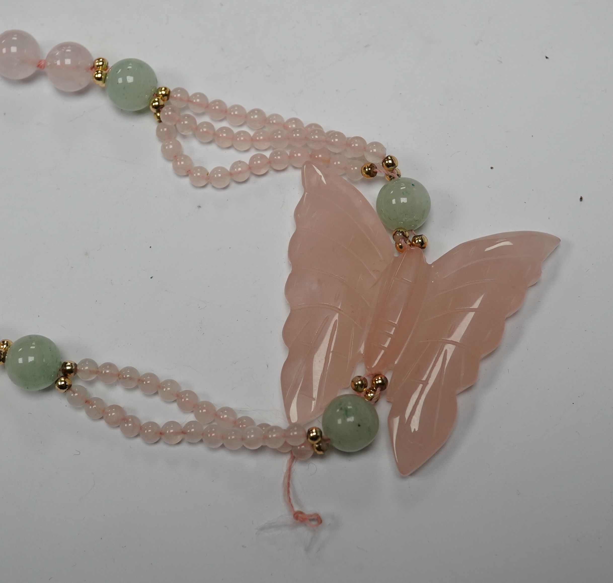 A recent rose quartz bead necklace, with central rose quartz butterfly and yellow metal and green quartz bead spacers, approx. 90cm. Condition - fair to good